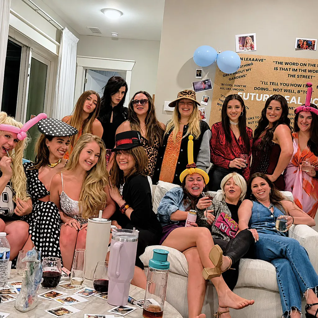 Bachelorette party guests in costumes and balloon hats on the couch in front of a Future Mrs photo board